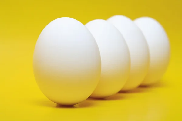 Четыре Яйца Белой Курицы Стоят Вертикально Желтом Фоне — стоковое фото