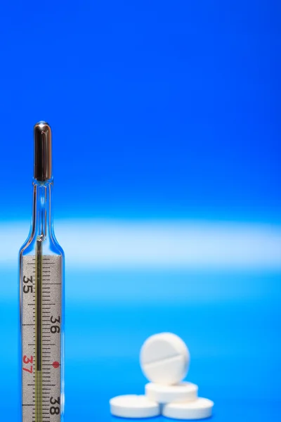 Empilement Pilules Près Thermomètre Clinique Sur Fond Bleu — Photo
