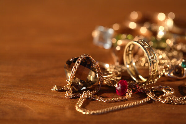 Closeup of pile of gold jewelry on wooden surface with lighting effect