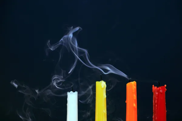 stock image Four color extinguished candles with smoke on black background