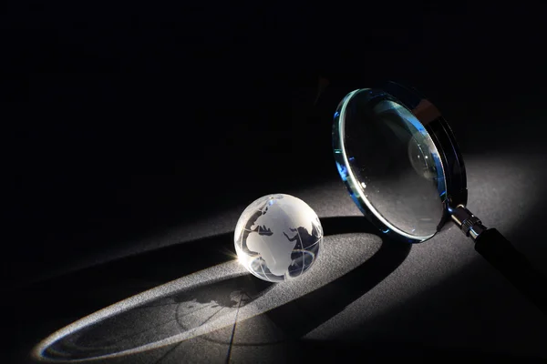 Lupe Und Globus Auf Dunklem Hintergrund Mit Lichtstrahl — Stockfoto
