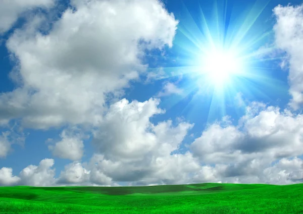 青い空と緑の空き地で雲の中の太陽 — ストック写真