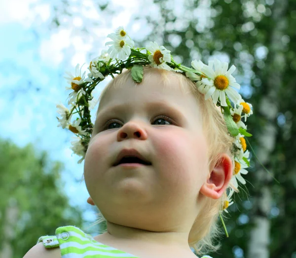 Ευτυχισμένη κοριτσάκι στο στεφάνι λουλούδια που βρίσκεται στο πράσινο λιβάδι — Φωτογραφία Αρχείου