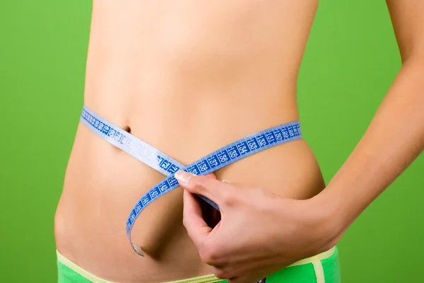 Mladá žena měření její štíhlé tělo — Stock fotografie
