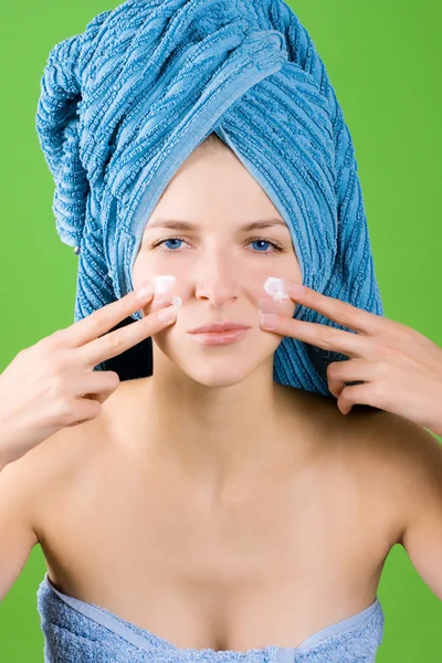 Mujer joven aplicando crema facial —  Fotos de Stock