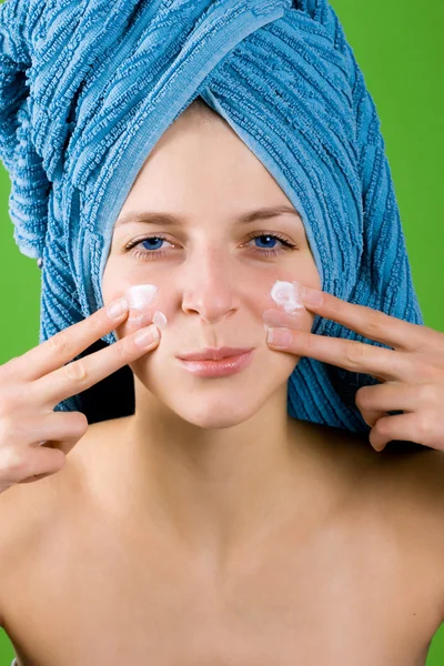 Nő a kék törölköző arc krém alkalmazása — Stock Fotó