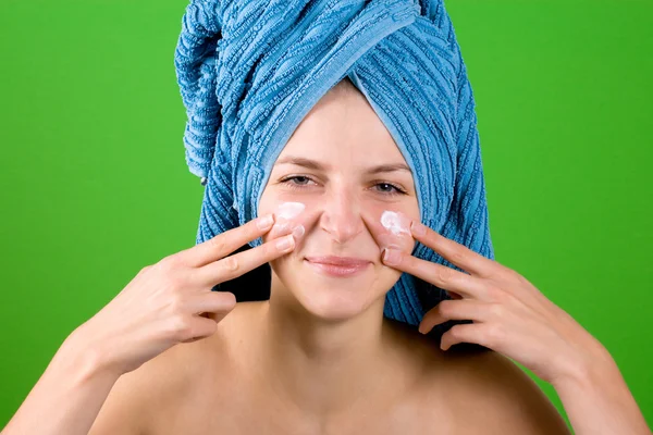 Young woman in blue towel applying facial cream — Stock Photo, Image