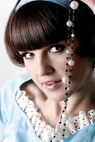 Brunette woman in blue dress with pearl beads — Stock Photo, Image