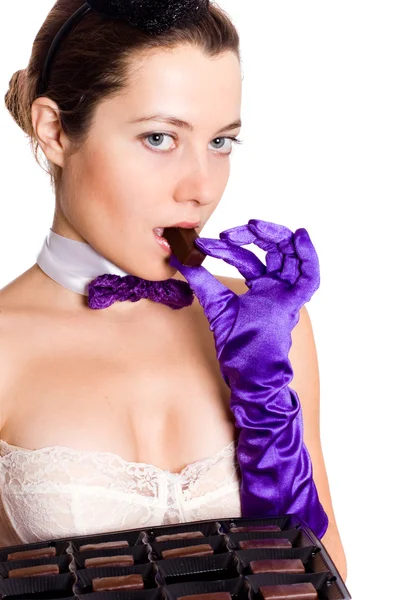 Woman in corset and little hat eating sweets — Stock Photo, Image