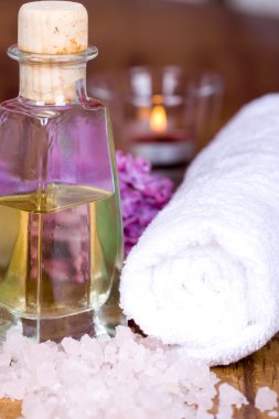 Bath and spa items (towel, salt, oil, lilac, candle) on wooden background clipart