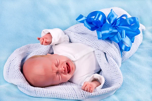 大きな青い弓によって固定されて泣いている新生児 — ストック写真