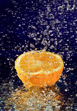 Half of orange with stopped motion water drops on deep blue clipart