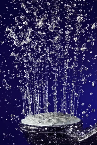 Hand douche douche met gestopt beweging water druppels op donkerblauw — Stockfoto