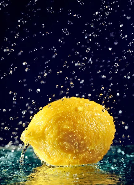Limón entero con gotas de agua de movimiento detenido en azul profundo — Foto de Stock