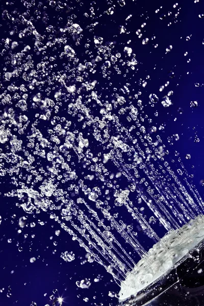 Ручной душ душ с остановленным движением воды капли на глубокой синей — стоковое фото
