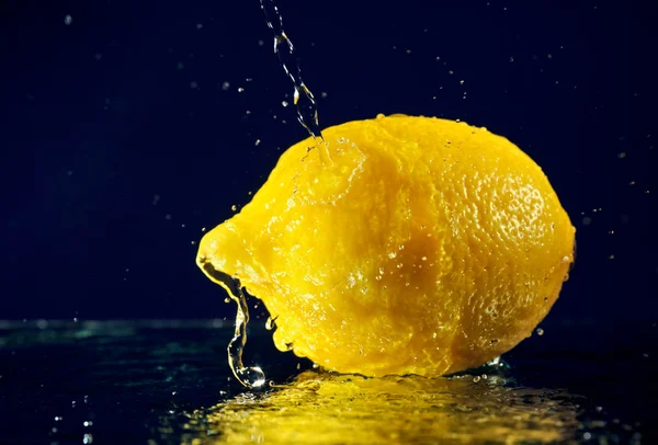 Цілий лимон із зупиненою рухомою водою падає на синій глибокий — стокове фото