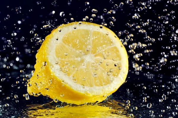 Setengah lemon dengan air gerak berhenti tetes pada hitam — Stok Foto