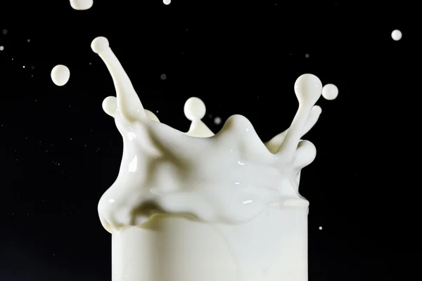 Glas mjölk med stänk droppar på djupt blå — Stockfoto