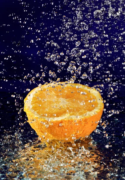 Половина апельсина з зупиненим рухом краплі води на глибокому синьому — стокове фото