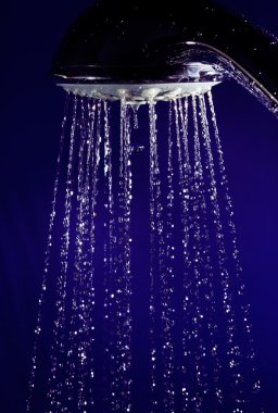 Hand shower douche with stopped motion water drops on deep blue clipart