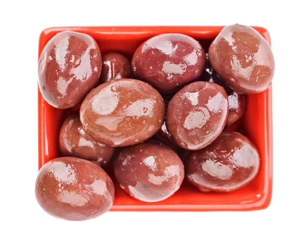 Aceitunas marrones en vinagre frutas en placa cuadrada roja aislada en whit — Foto de Stock