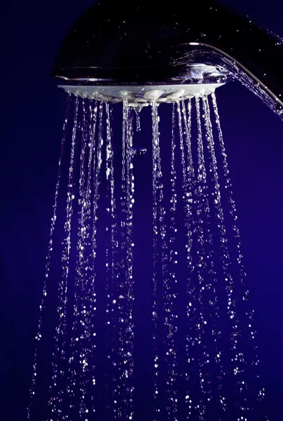 Douche douche à main avec gouttes d'eau à mouvement arrêté sur bleu profond — Photo