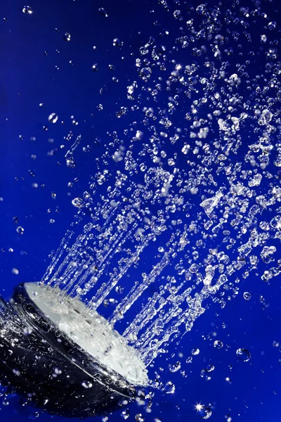 Ducha de ducha de mano con gotas de agua de movimiento detenido en azul profundo — Foto de Stock