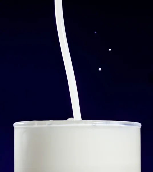 Glas melk met spatten druppels op donkerblauw — Stockfoto