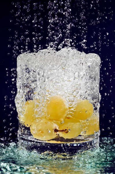 Гроздь белого винограда, падающая в стакан с водой на глубину b — стоковое фото
