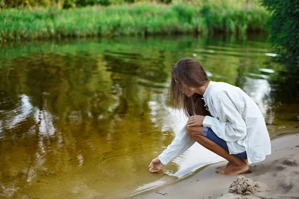 Vacker ung kvinna byggnad sand slott utmed sjön — Stockfoto