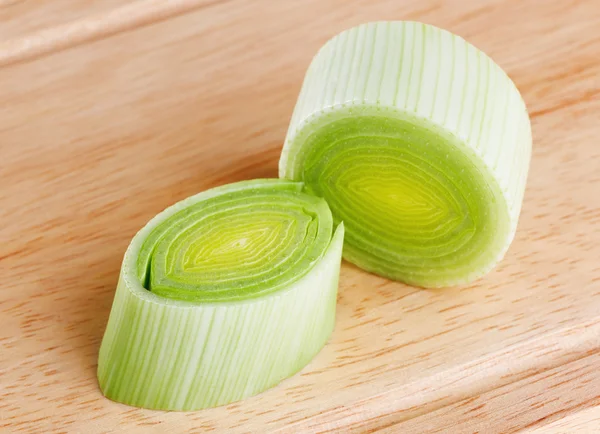 Cross-section of green leek on wooden chopping board — Stock Photo, Image