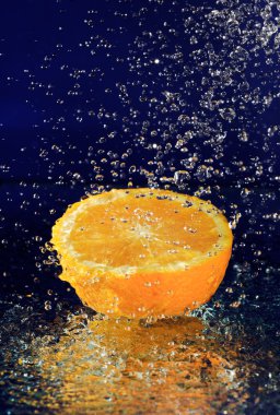 Half of orange with stopped motion water drops on deep blue clipart