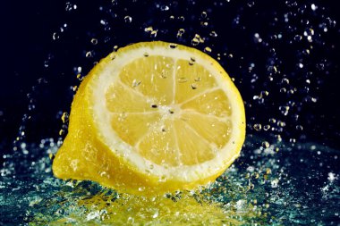 Half of lemon with stopped motion water drops on black clipart