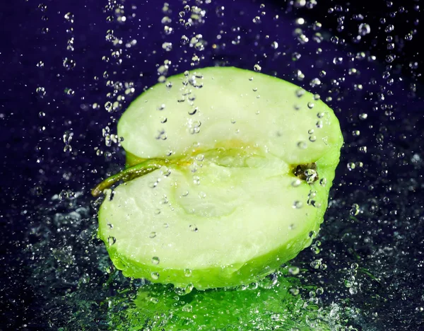 Hälften av grönt äpple med stoppad rörelse vatten droppar på djupt blå — Stockfoto