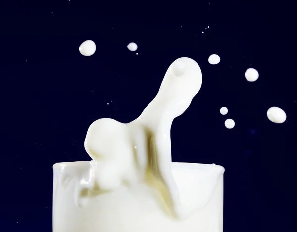 一杯牛奶与溅落在深蓝色 — 图库照片