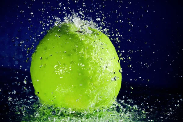 แอปเปิ้ลสีเขียวทั้งหมดที่มีการหยุดการเคลื่อนไหว น้ําหยดบนสีฟ้าลึก — ภาพถ่ายสต็อก