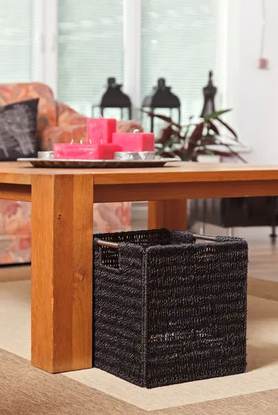 Плетеная корзина газеты под деревянным столом — стоковое фото