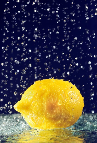 Limão inteiro com gotas de água de movimento parado em azul profundo — Fotografia de Stock