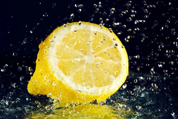 Metade de limão com gotas de água de movimento parado em preto — Fotografia de Stock