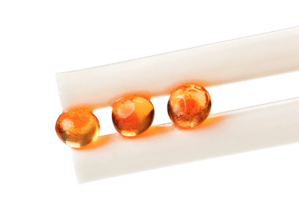 Three red salmon caviar ball in chopsticks — Stock Photo, Image