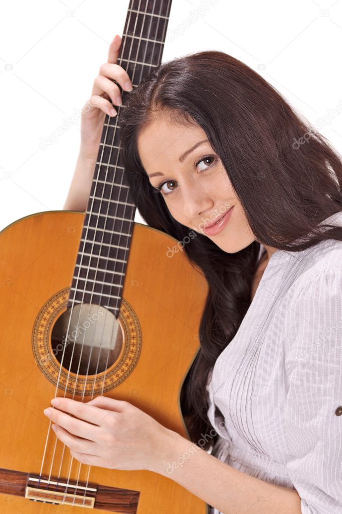 Young beautiful smiling brunette lady in white chemise playing acoustic guitar