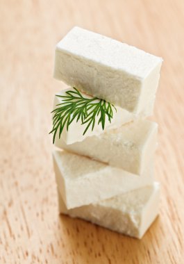 Feta cheese cubes with dill twig on wooden chopping board clipart