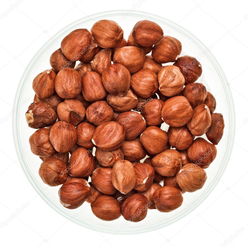Unshelled hazel nuts in a glass bowl isolated on white
