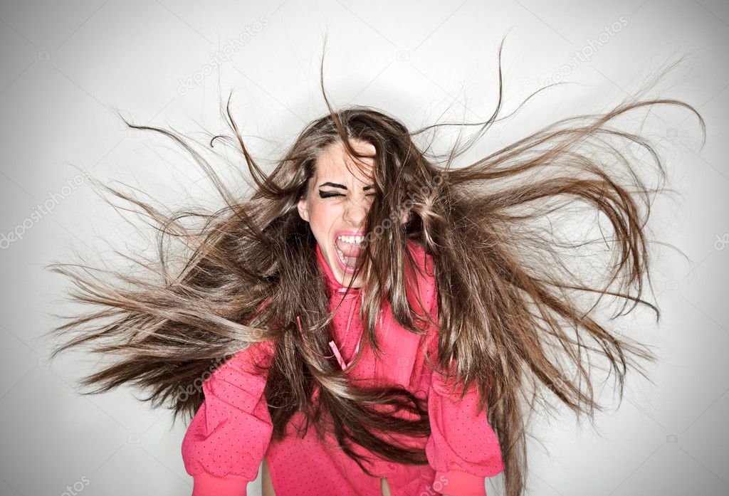 Screaming furious aggressive brunette woman with flying long hai