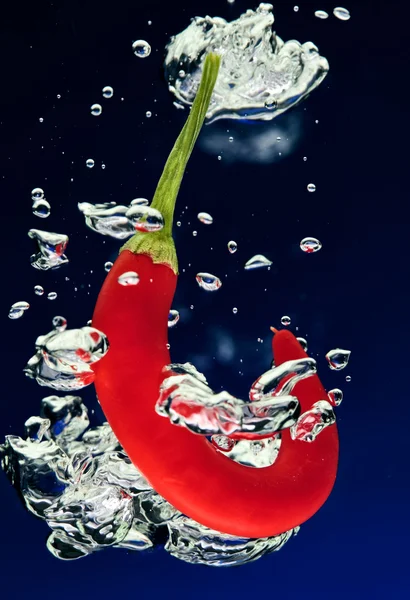 Chilli pepper falling in water with air bubbles — Stock Photo, Image