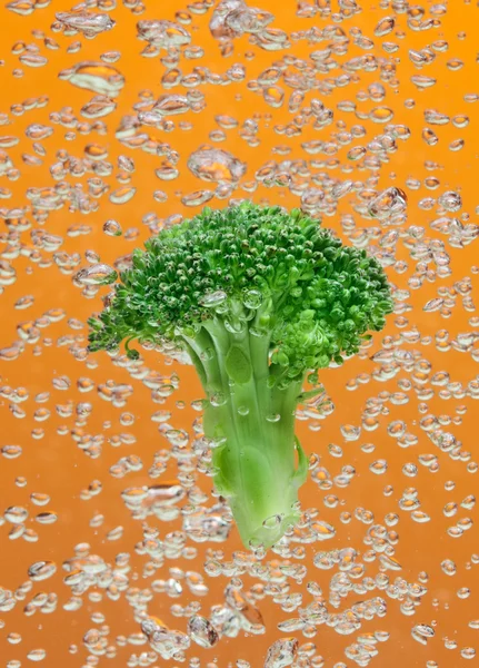 Brócolos verdes caindo na água com bolhas de ar — Fotografia de Stock