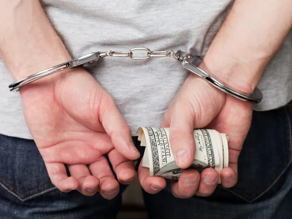 Handcuffs on hands holding money — Stock Photo, Image