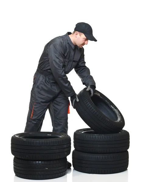 年轻的机械师移动隔离在白色背景上的轮胎 — 图库照片