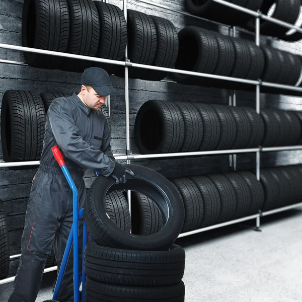 白种人机修工构成轮胎对车辆和 车库背景 — 图库照片