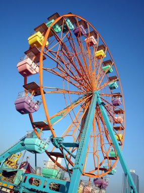 A ferris wheel with colorful cabins at a local fun fair clipart